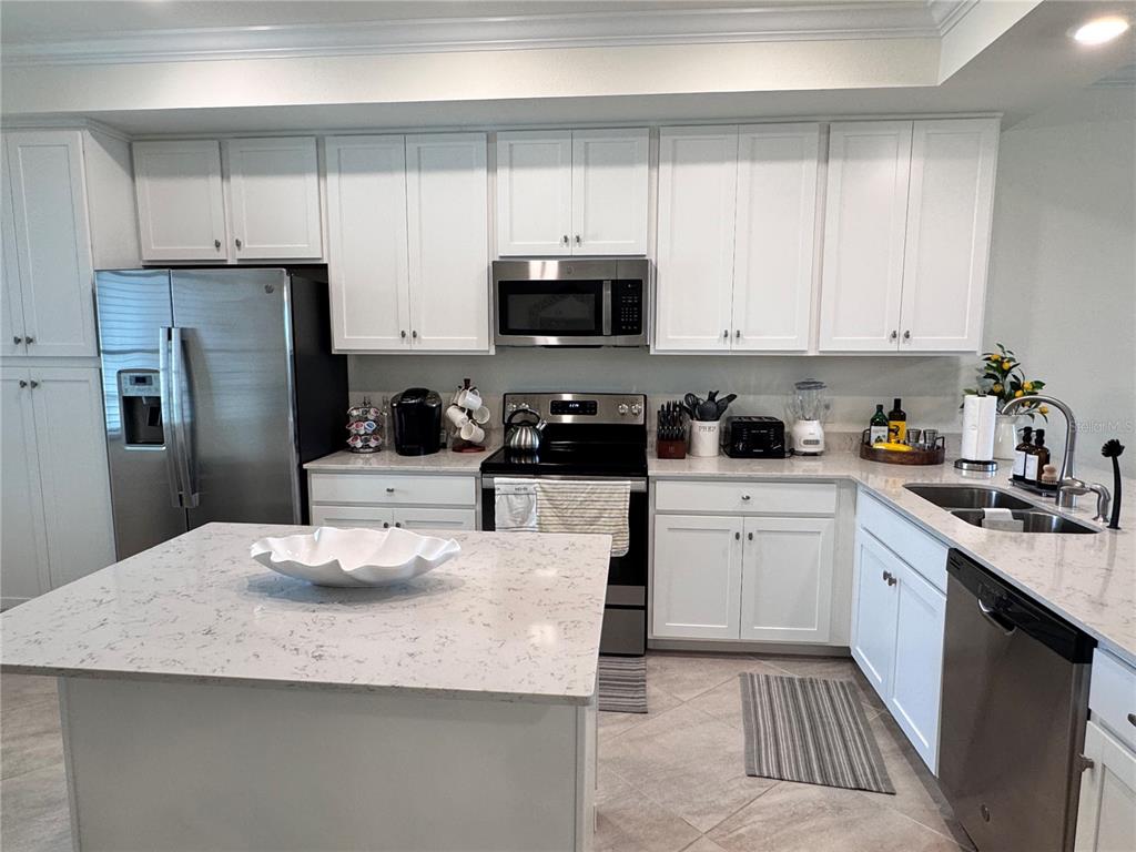 A kitchen features white cabinets, stainless steel appliances, and a quartz-topped island — 17724 GAWTHROP DRIVE UNIT 304, BRADENTON, FL