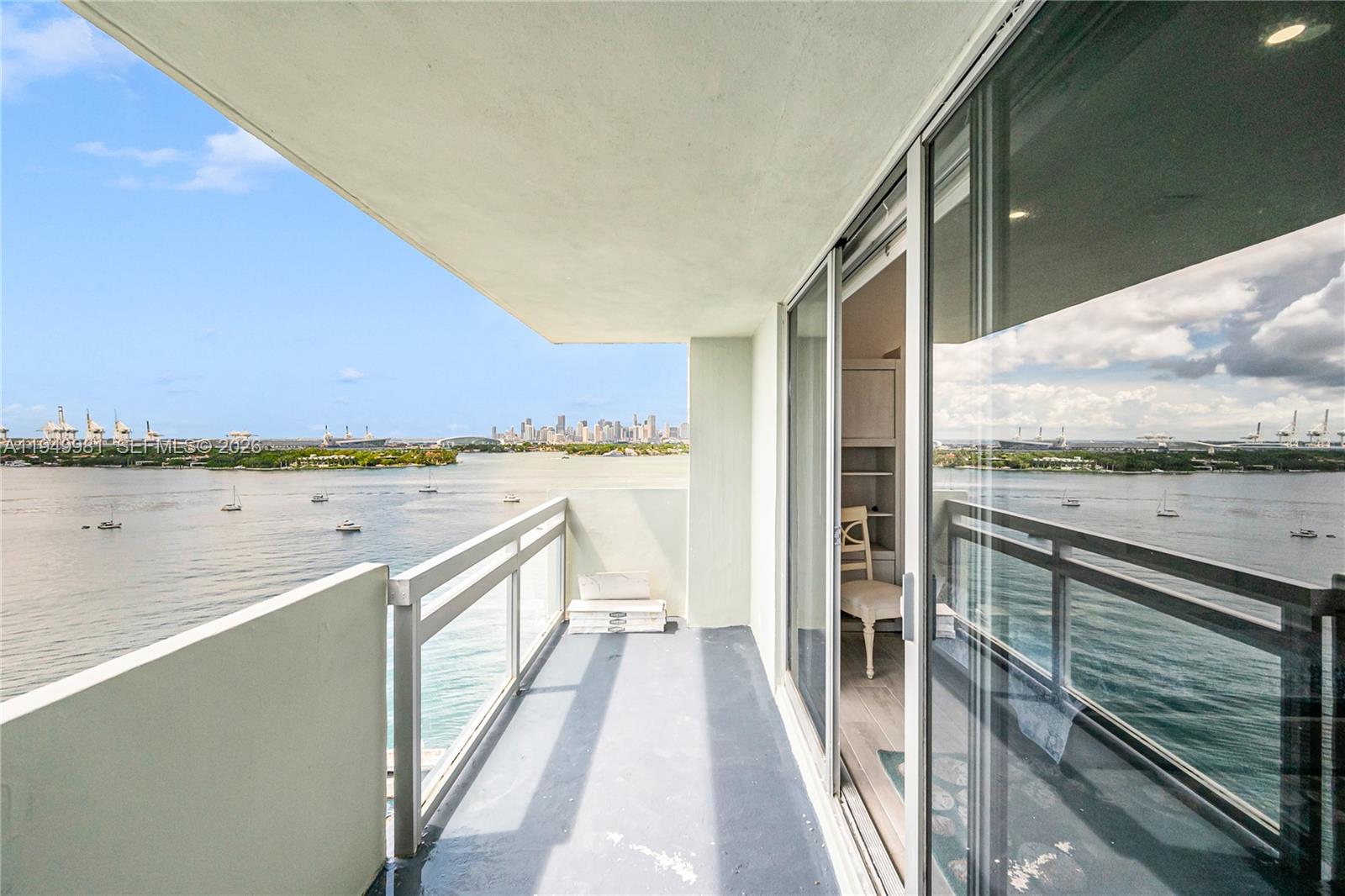 A balcony with a gray floor overlooks a bay with a city skyline in the distance — 1500 Bay Rd # 1536S, Miami Beach FL 33139, MIAMI BEACH, FL