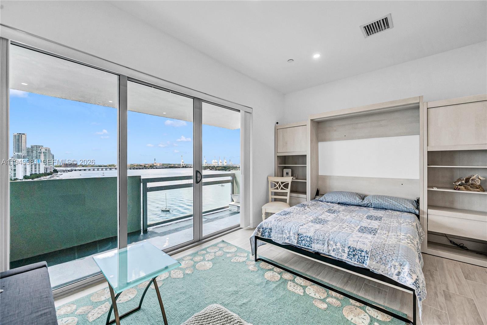 A bedroom features a Murphy bed, light wood cabinetry, and a balcony overlooking the water — 1500 Bay Rd # 1536S, Miami Beach FL 33139, MIAMI BEACH, FL