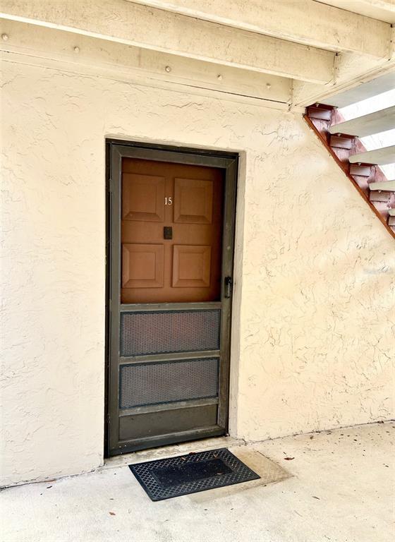 A brown door with a screen and the number 15 is set into a textured wall — 506 ORANGE DRIVE UNIT 15, ALTAMONTE SPRINGS, FL