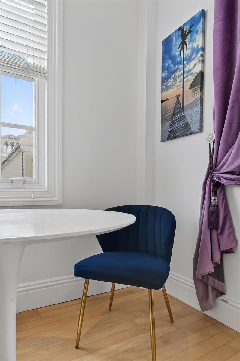 A white table and a blue velvet chair sit near a window and purple curtains — 235 Sunrise Avenue # 3265, Palm Beach FL 33480, PALM BEACH, FL