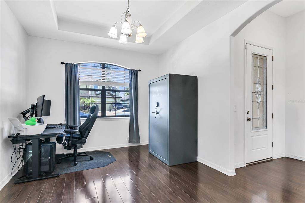 A home office with dark wood floors, a large gun safe, and a desk by a window — 12514 BALLENTRAE FOREST DRIVE, RIVERVIEW, FL