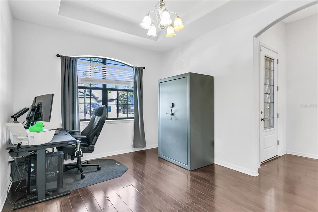 A home office with dark hardwood floors, a large gun safe, and a computer desk — 12514 BALLENTRAE FOREST DRIVE, RIVERVIEW, FL