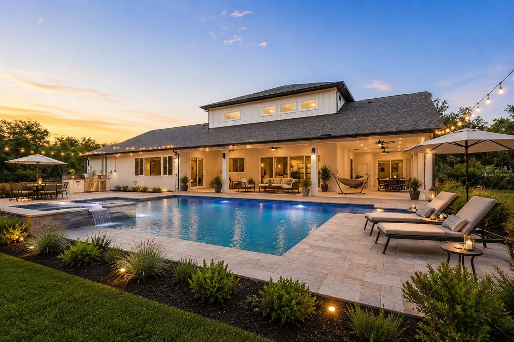 A modern house with a pool, patio, and outdoor living area at sunset — 12000 GOLDEN VALLEY DRIVE, NEW PORT RICHEY, FL
