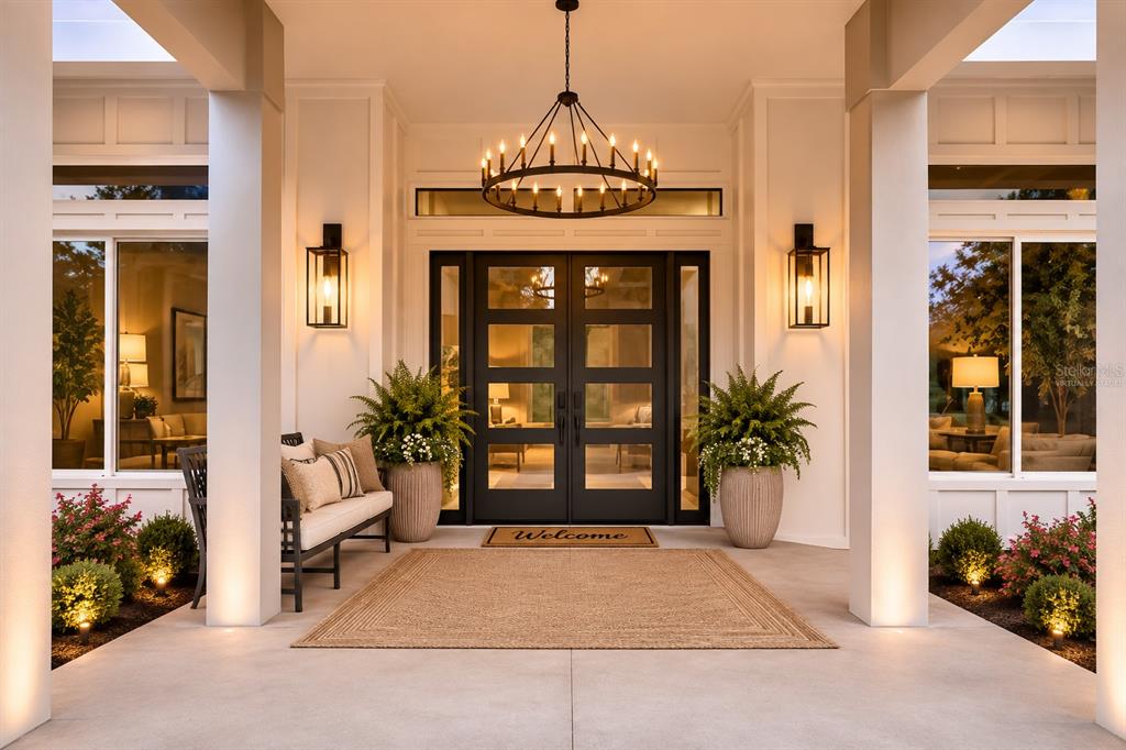 A covered front porch features a double door entrance, a chandelier, and potted ferns — 12000 GOLDEN VALLEY DRIVE, NEW PORT RICHEY, FL