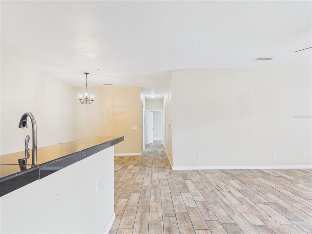 A kitchen island with a dark countertop overlooks a living area with wood-look tile flooring — 16305 ENCLAVE VILLAGE DRIVE UNIT 102, TAMPA, FL