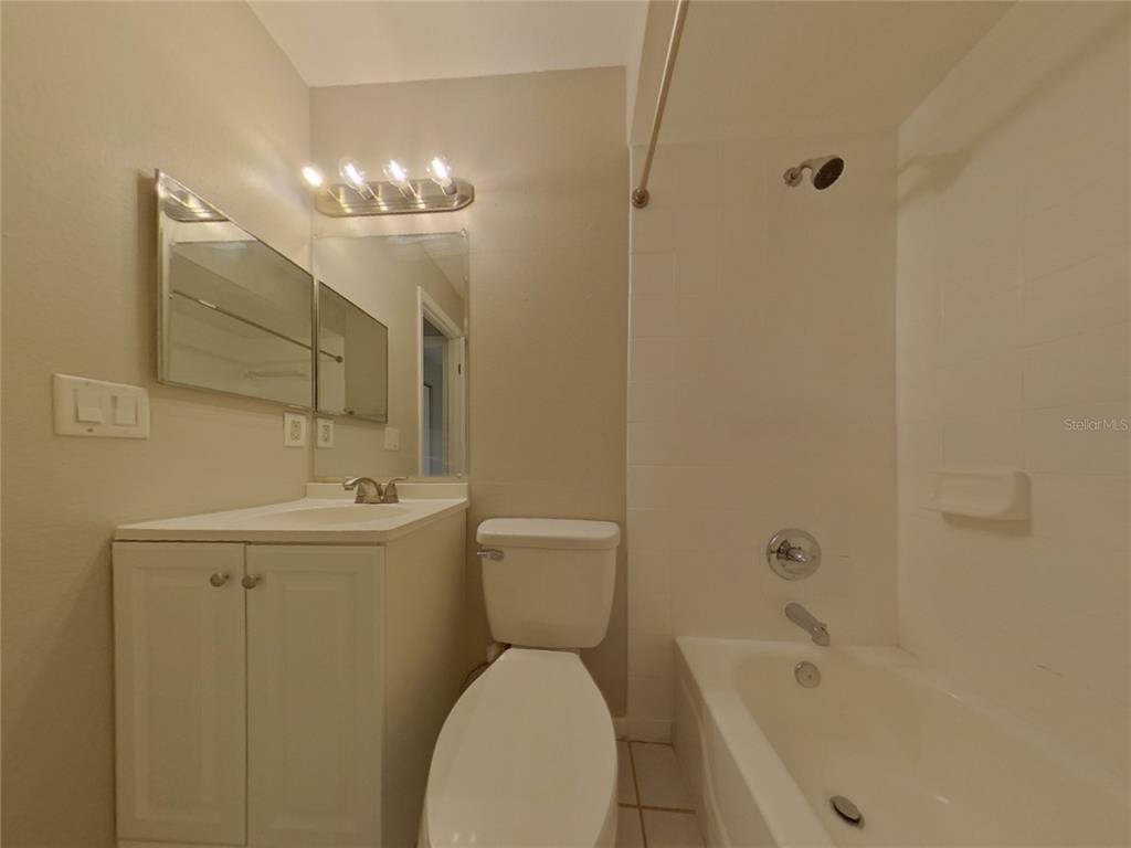 A bathroom features a white vanity, a toilet, and a shower-tub combination with white tile — 1627 PENDLETON STREET, DELTONA, FL