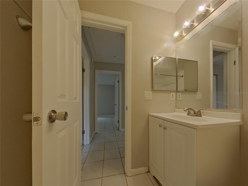 A bathroom features a white vanity, a medicine cabinet, and a view into a hallway — 1627 PENDLETON STREET, DELTONA, FL