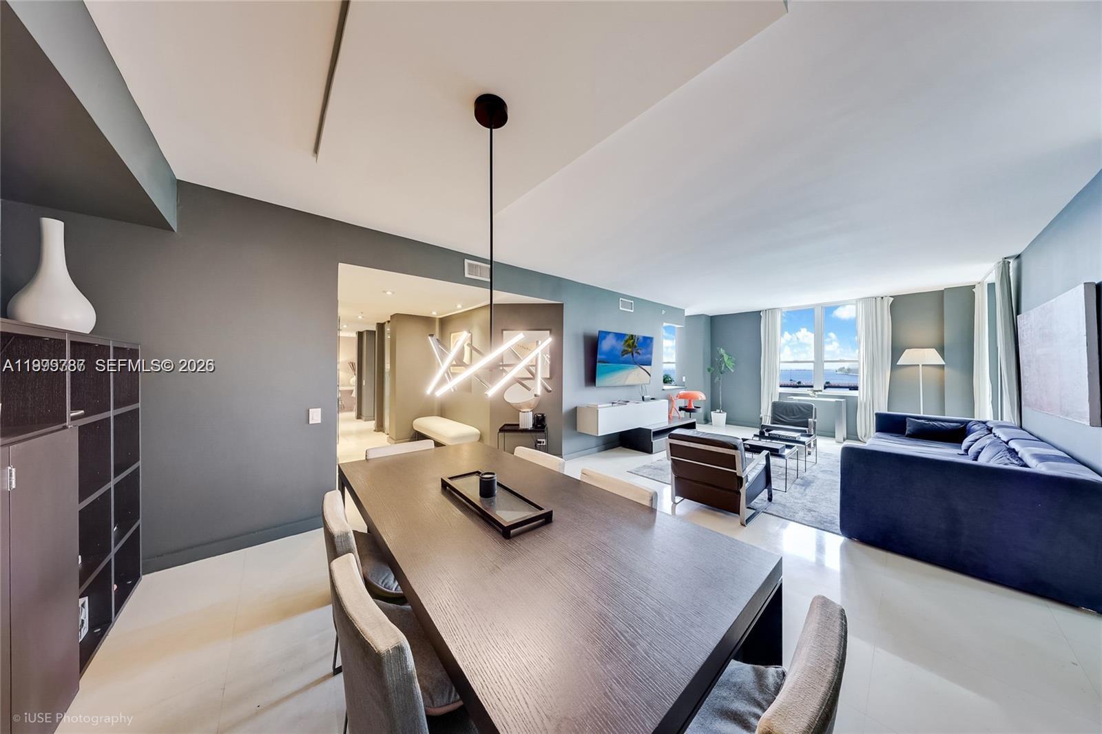 A modern dining area with a dark wood table leads into a living room — 701 Brickell Key Blvd # 503, Miami FL 33131, MIAMI, FL