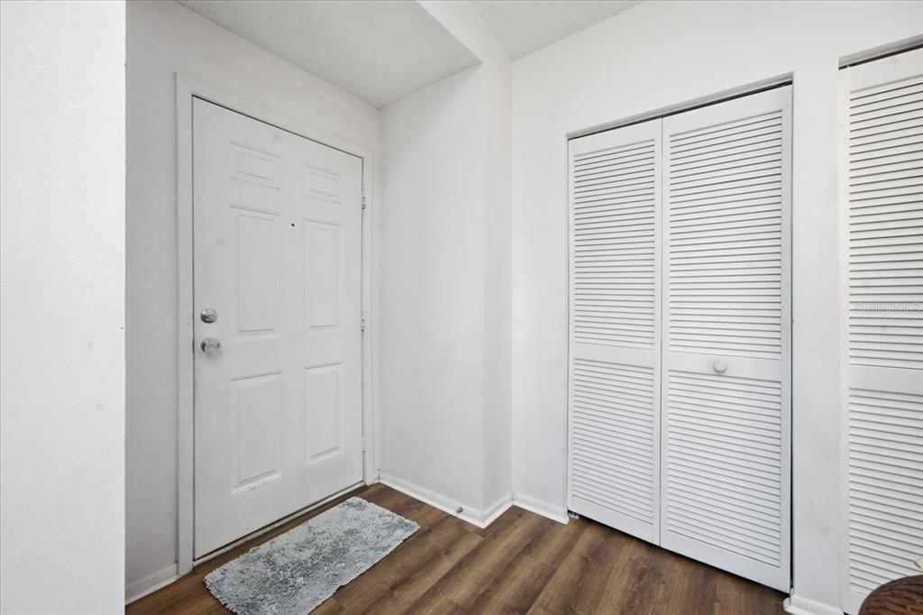 An entryway features a white front door, a louvered closet, and wood-look flooring — 9436 NAKOMA WAY UNIT 9436, WEEKI WACHEE, FL