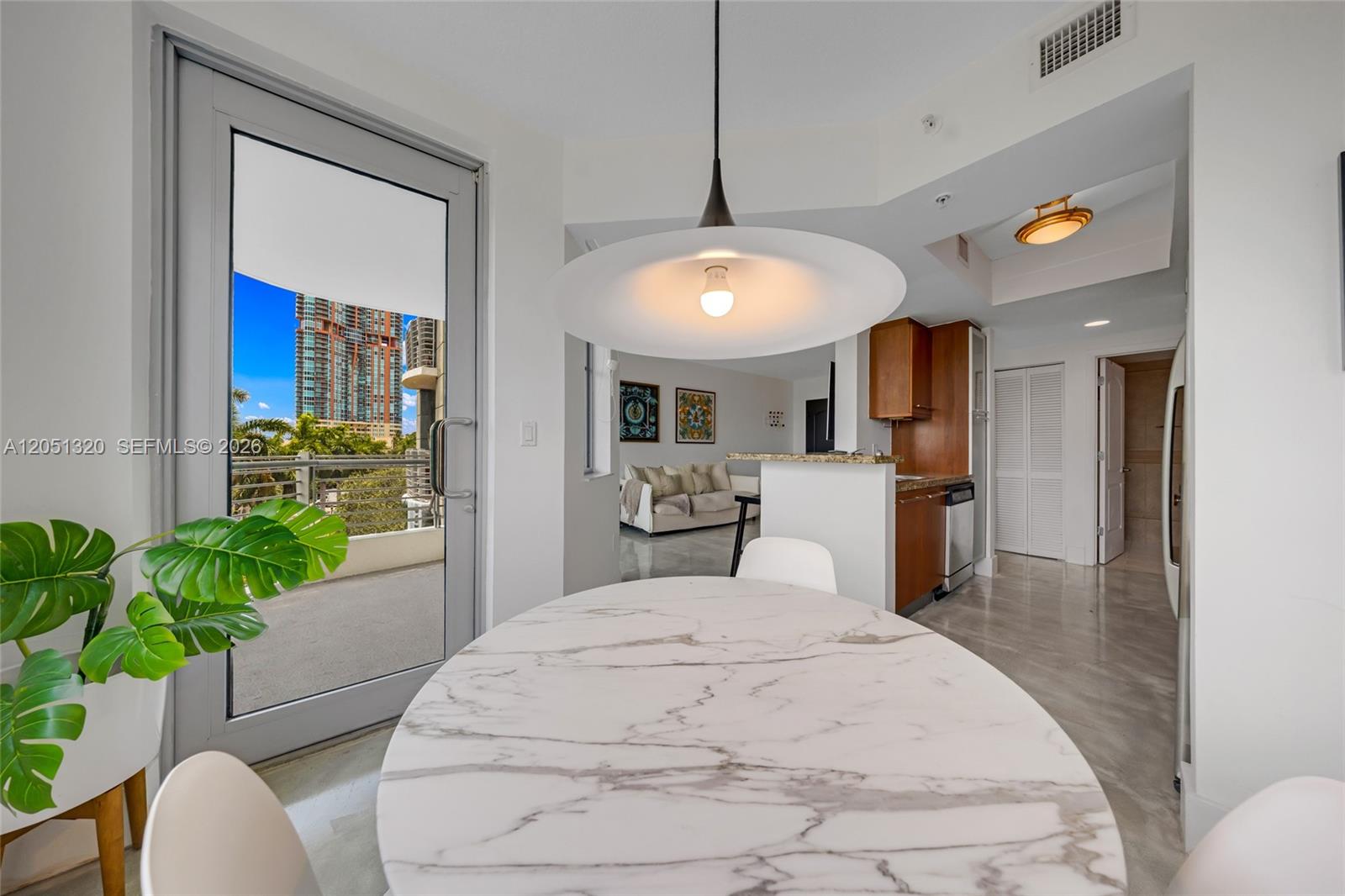 A dining area features a marble table, a large pendant light, and a balcony view — 110 Washington Ave # 2505, Miami Beach FL 33139, MIAMI BEACH, FL