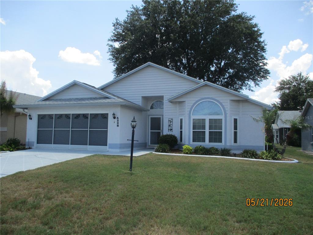 A single-story house with a white exterior, a garage, and a large front yard — 6228 EGRET DRIVE, LAKELAND, FL