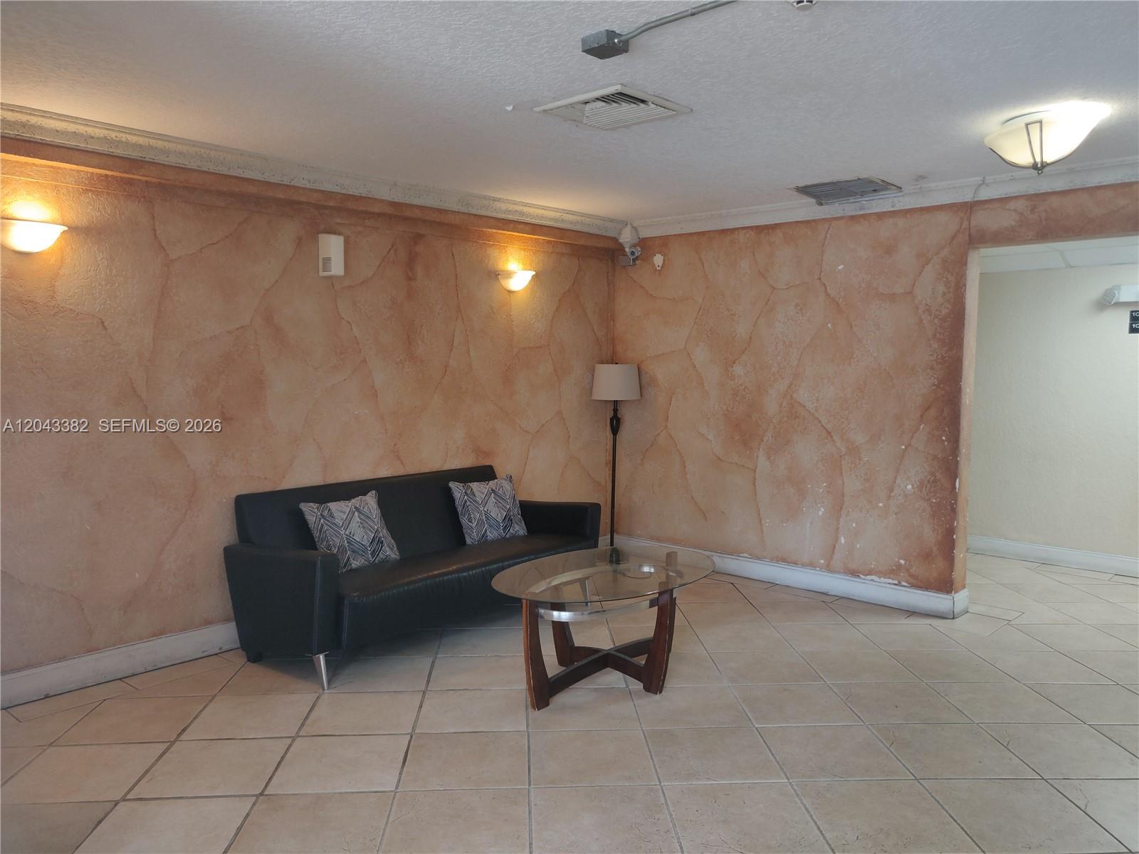 A waiting area features a black sofa, glass coffee table, and faux-finish textured walls — 9001 SW 77th Ave # C606, Miami FL 33156, MIAMI, FL