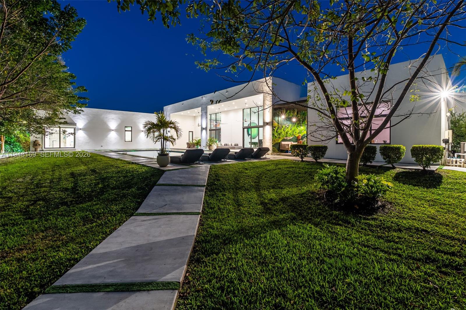A modern white house with a pool and patio at night — 6175 SW 128th Street, Pinecrest FL 33156, PINECREST, FL