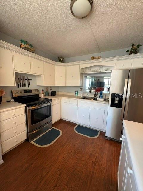 A kitchen features white cabinetry, stainless steel appliances, and wood-look flooring — 7920 SUN ISLAND DRIVE S UNIT 205, SOUTH PASADENA, FL