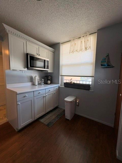 A kitchen features white cabinets, a built-in microwave, a window with blinds, and wood flooring — 7920 SUN ISLAND DRIVE S UNIT 205, SOUTH PASADENA, FL