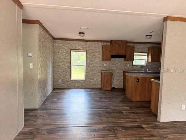 A kitchen with wood cabinets and a center island features wood-look flooring and textured walls — 1848 SE 178TH STREET, SUMMERFIELD, FL