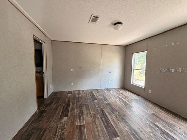 An empty room with wood-look flooring, light-colored walls, a window, and a doorway — 1848 SE 178TH STREET, SUMMERFIELD, FL