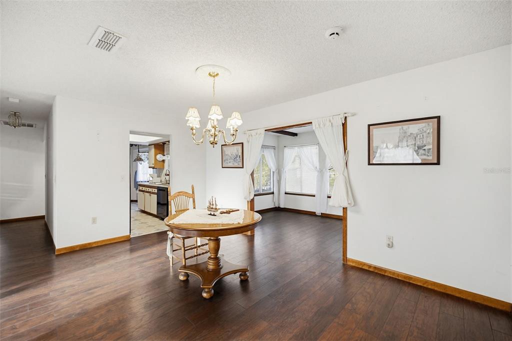A dining area features dark wood flooring, a round pedestal table, and a chandelier — 10952 SW 75TH AVENUE, OCALA, FL