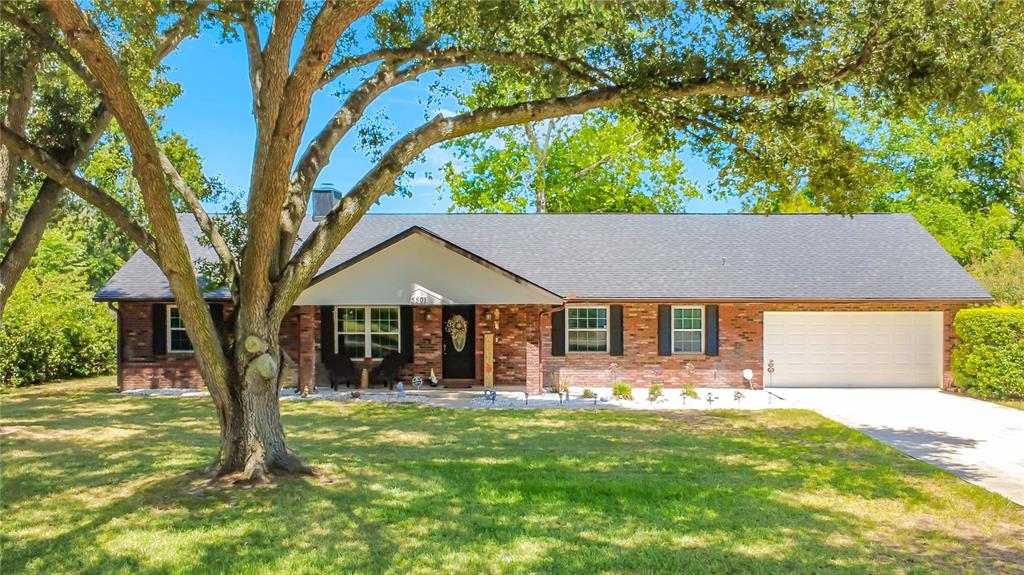 A single-story brick house with a white garage door and a large tree in front — 5501 SE 42ND COURT, OCALA, FL