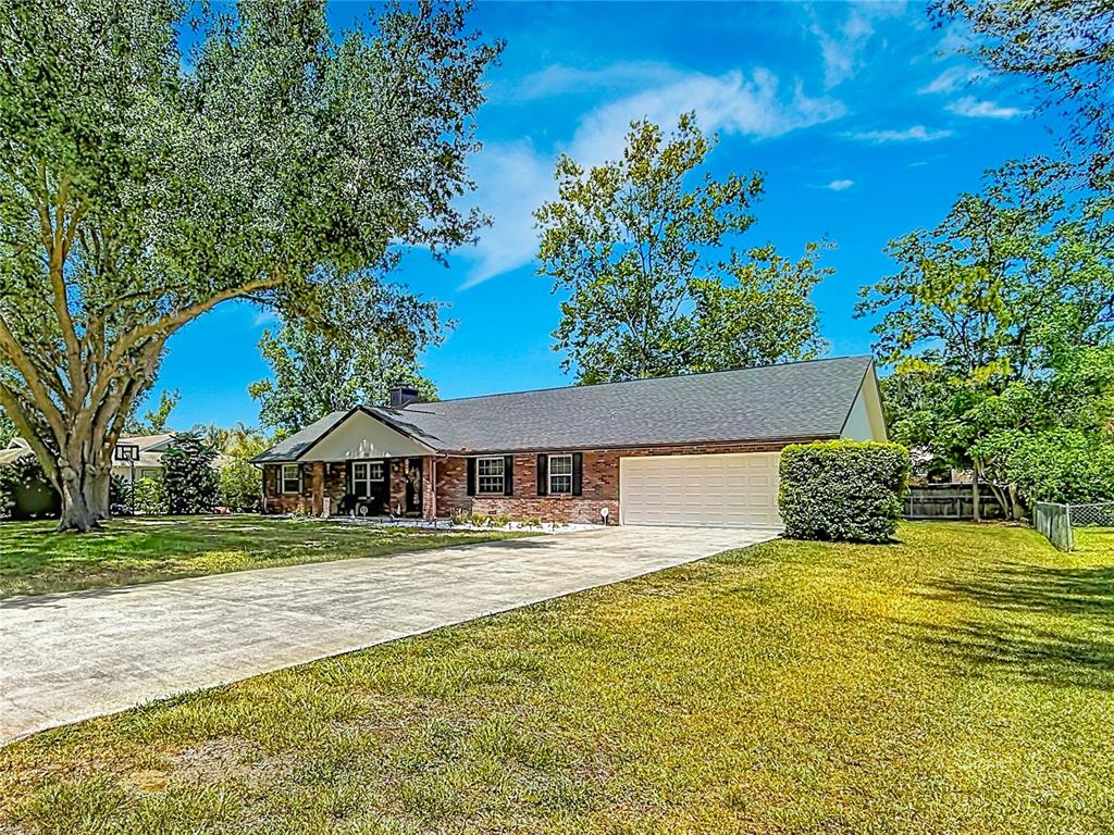 A single-story brick house with a large lawn, concrete driveway, and attached two-car garage — 5501 SE 42ND COURT, OCALA, FL