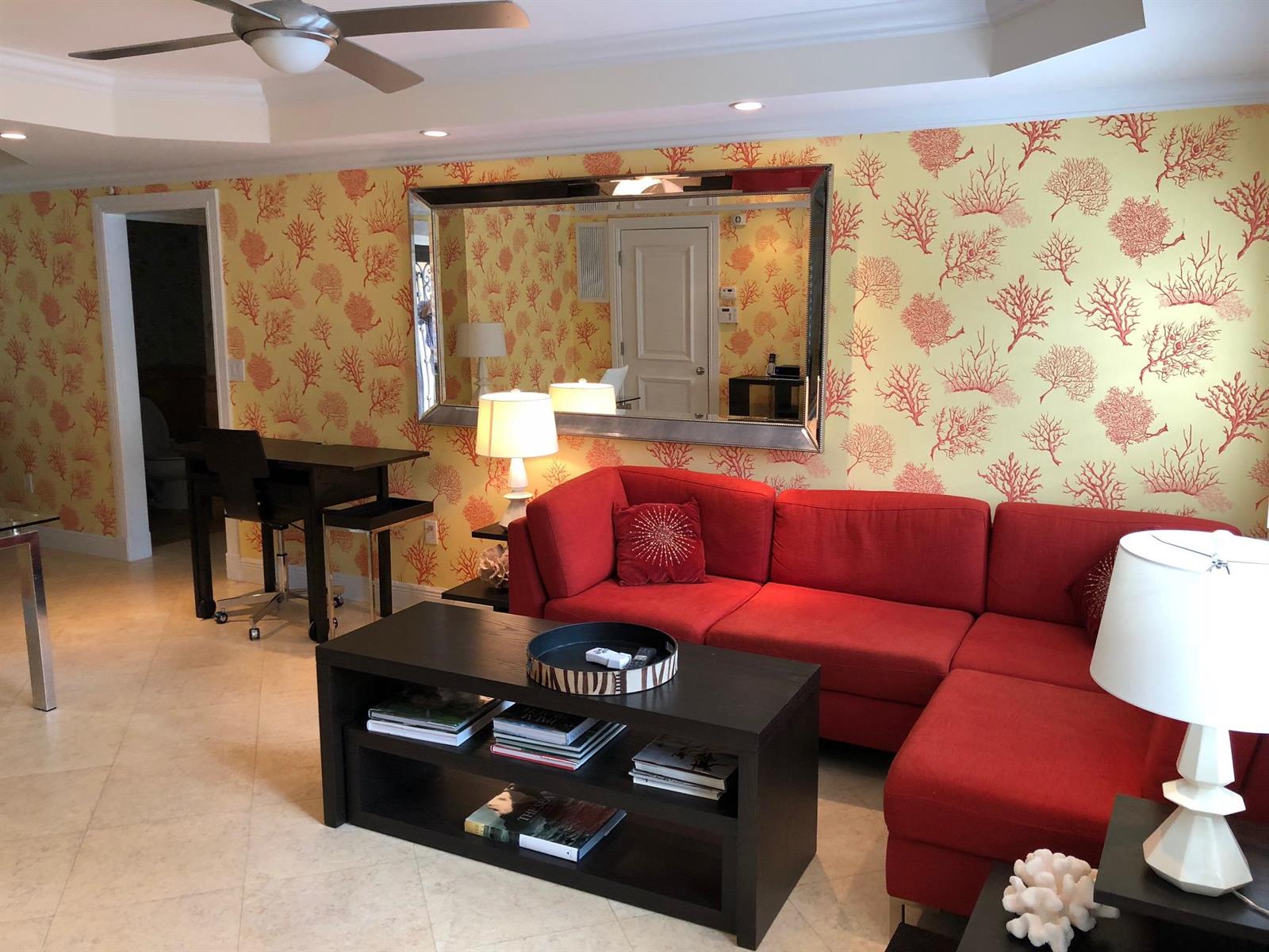 A living room features a red sectional sofa, a dark coffee table, and coral-patterned wallpaper — 251 Oleander Avenue # 1, Palm Beach FL 33480, PALM BEACH, FL