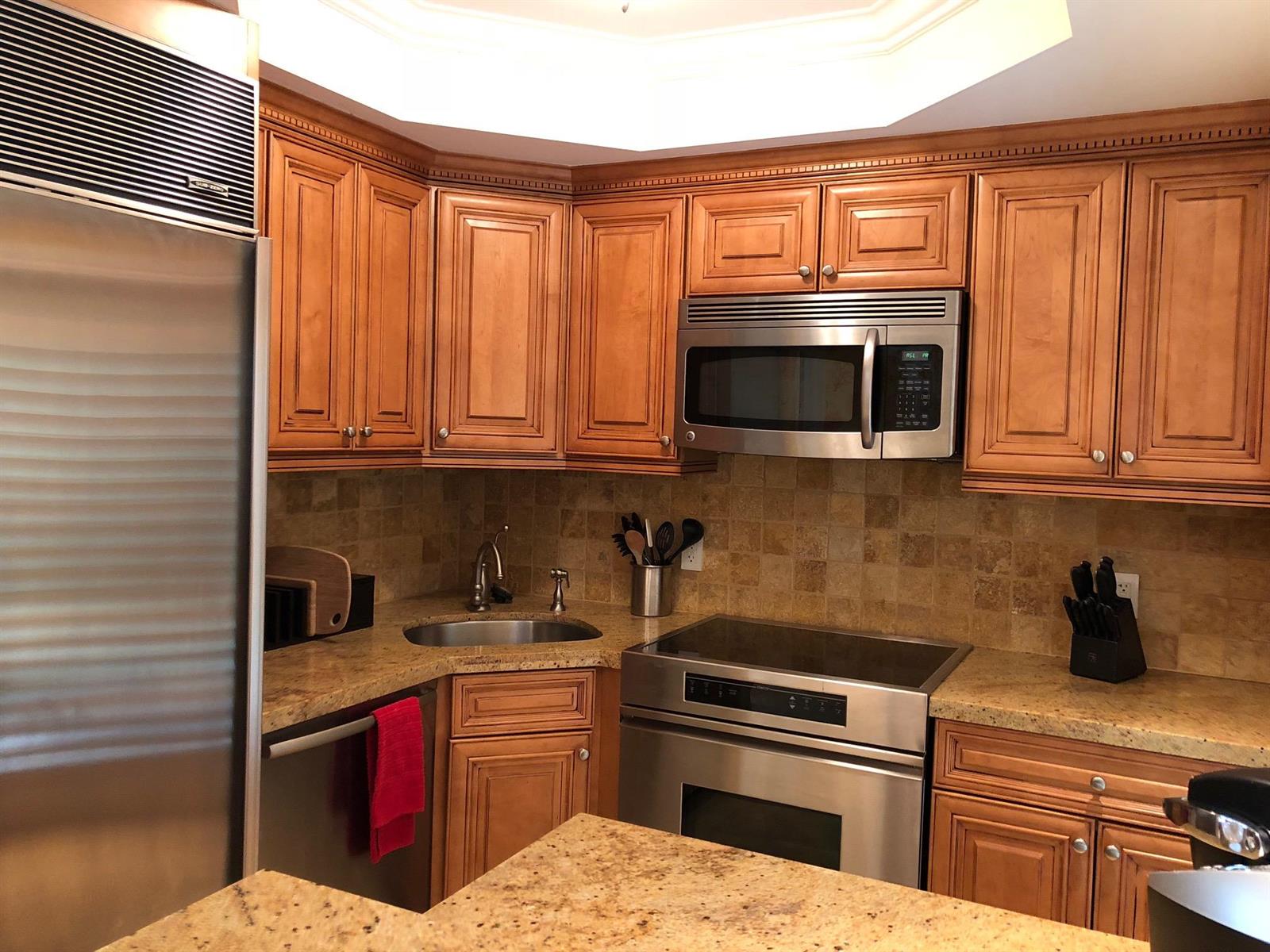 A kitchen features wood cabinets, granite countertops, stainless steel appliances, and a tiled backsplash — 251 Oleander Avenue # 1, Palm Beach FL 33480, PALM BEACH, FL