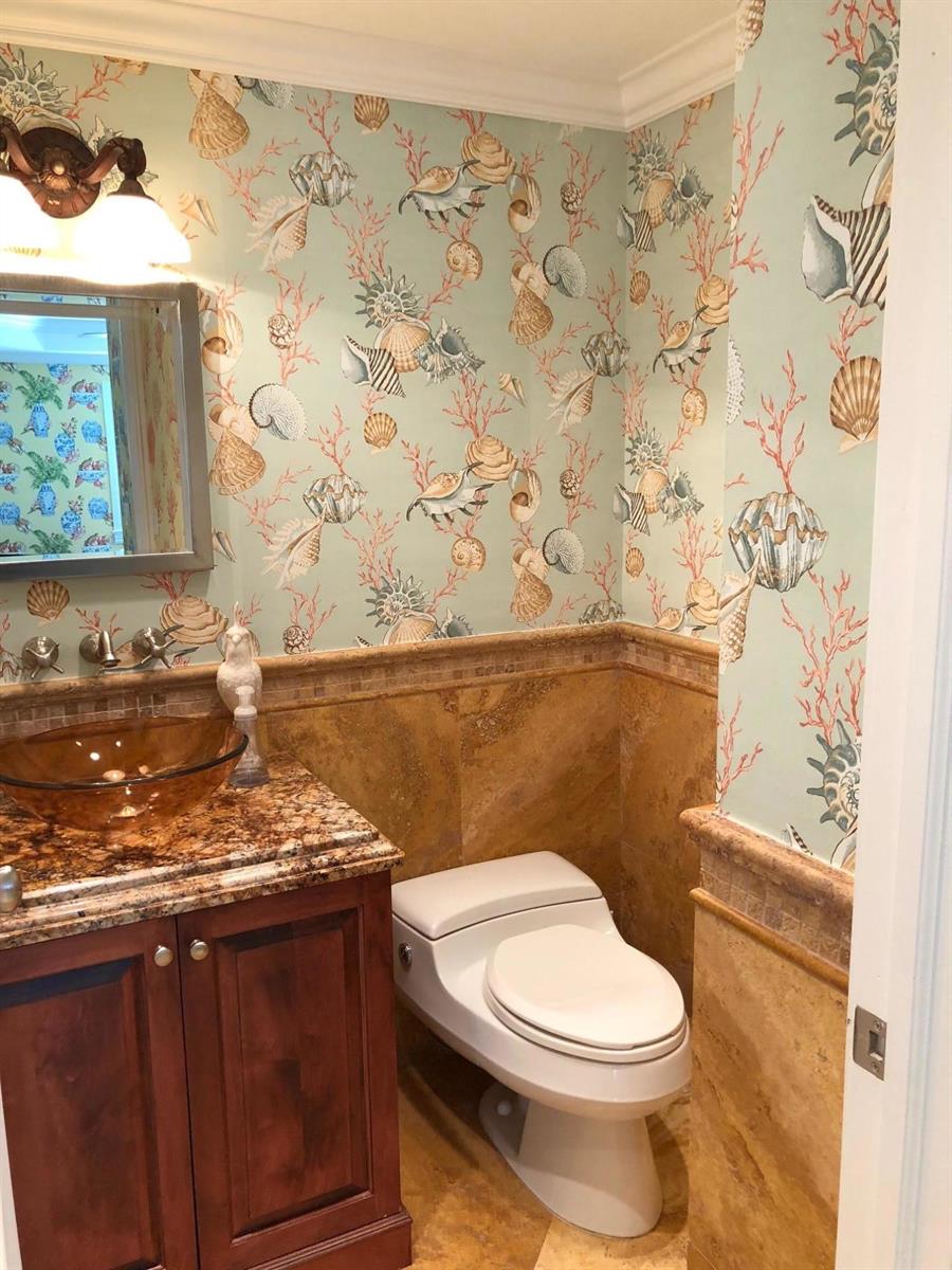A powder room features seashell wallpaper, a brown stone vanity, and a glass vessel sink — 251 Oleander Avenue # 1, Palm Beach FL 33480, PALM BEACH, FL