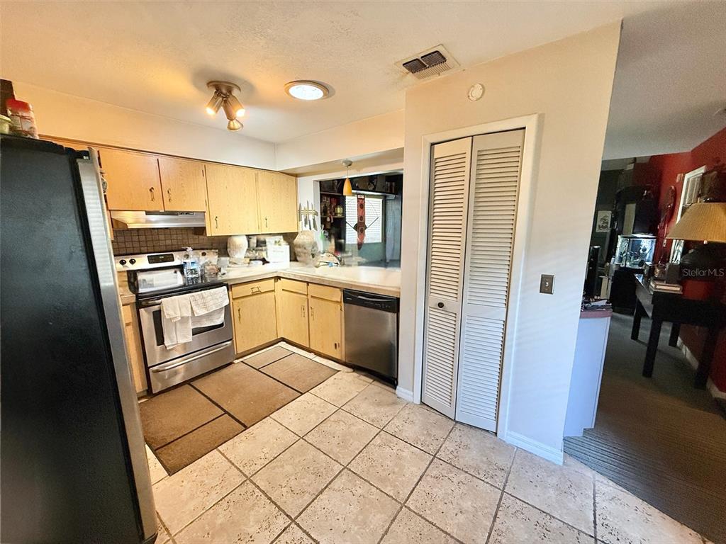 A kitchen features light wood cabinets, stainless steel appliances, and beige tile flooring — 7137 MARVISTA COURT, ORLANDO, FL