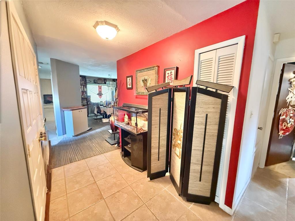 An entryway features a red accent wall, a folding room divider, and tiled flooring — 7137 MARVISTA COURT, ORLANDO, FL