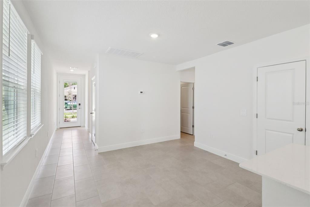 A bright, empty room features light tile flooring, white walls, and a glass-paneled exterior door — 803 SUNSHOWER DRIVE, LADY LAKE, FL