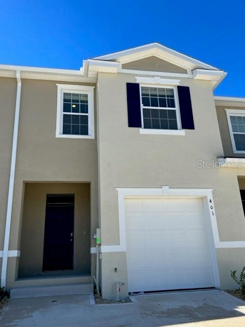 A two-story townhouse exterior features a single-car garage, a recessed front door, and beige siding — 401 FELTRIM RESERVE BOULEVARD, DAVENPORT, FL