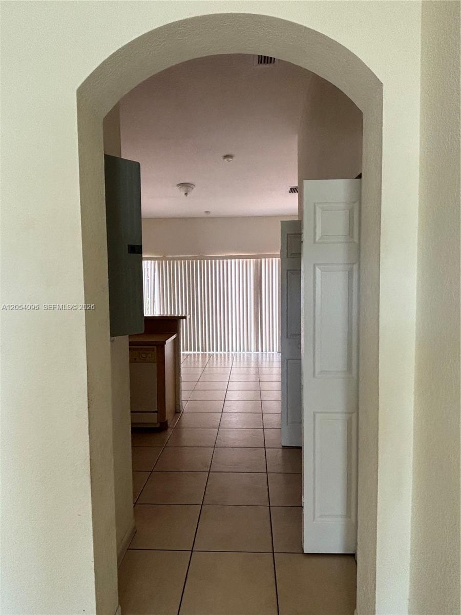 An arched doorway leads to a tiled room with a kitchen counter and vertical blinds — 13781 SW 171st Ter, Miami FL 33177, MIAMI, FL