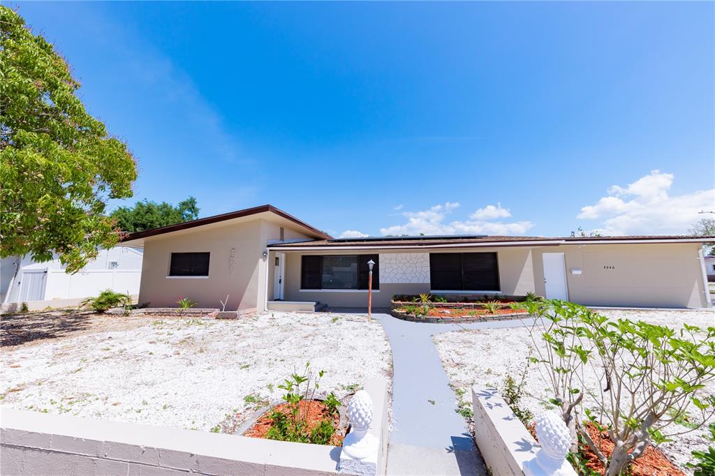 A single-story house with a flat roof, beige exterior, and a gravel front yard — 4946 DR MARTIN LUTHER KING JR STREET S, ST PETERSBURG, FL