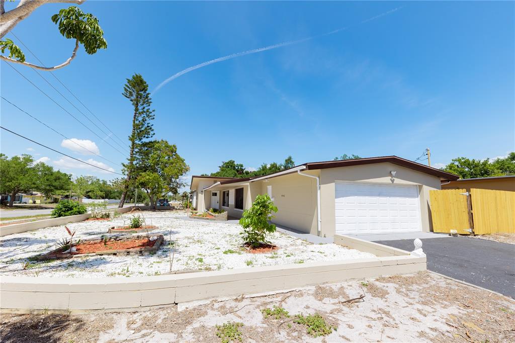 A single-story house with a white garage door, tan exterior, and a gravel front yard — 4946 DR MARTIN LUTHER KING JR STREET S, ST PETERSBURG, FL