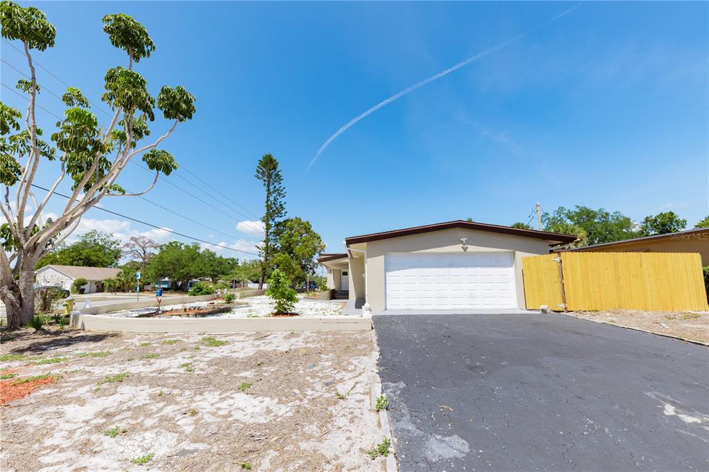 A single-story house with a white garage door, asphalt driveway, and a low retaining wall — 4946 DR MARTIN LUTHER KING JR STREET S, ST PETERSBURG, FL