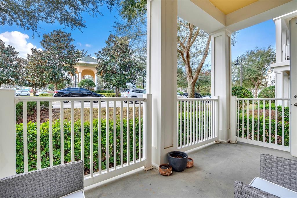 A covered patio features white railings, concrete flooring, and views of trees and a gazebo — 7501 MOURNING DOVE CIRCLE UNIT 103, REUNION, FL