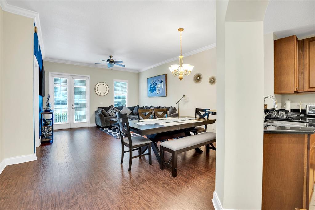 A dining area with a wooden table and bench connects to a living room — 7501 MOURNING DOVE CIRCLE UNIT 103, REUNION, FL