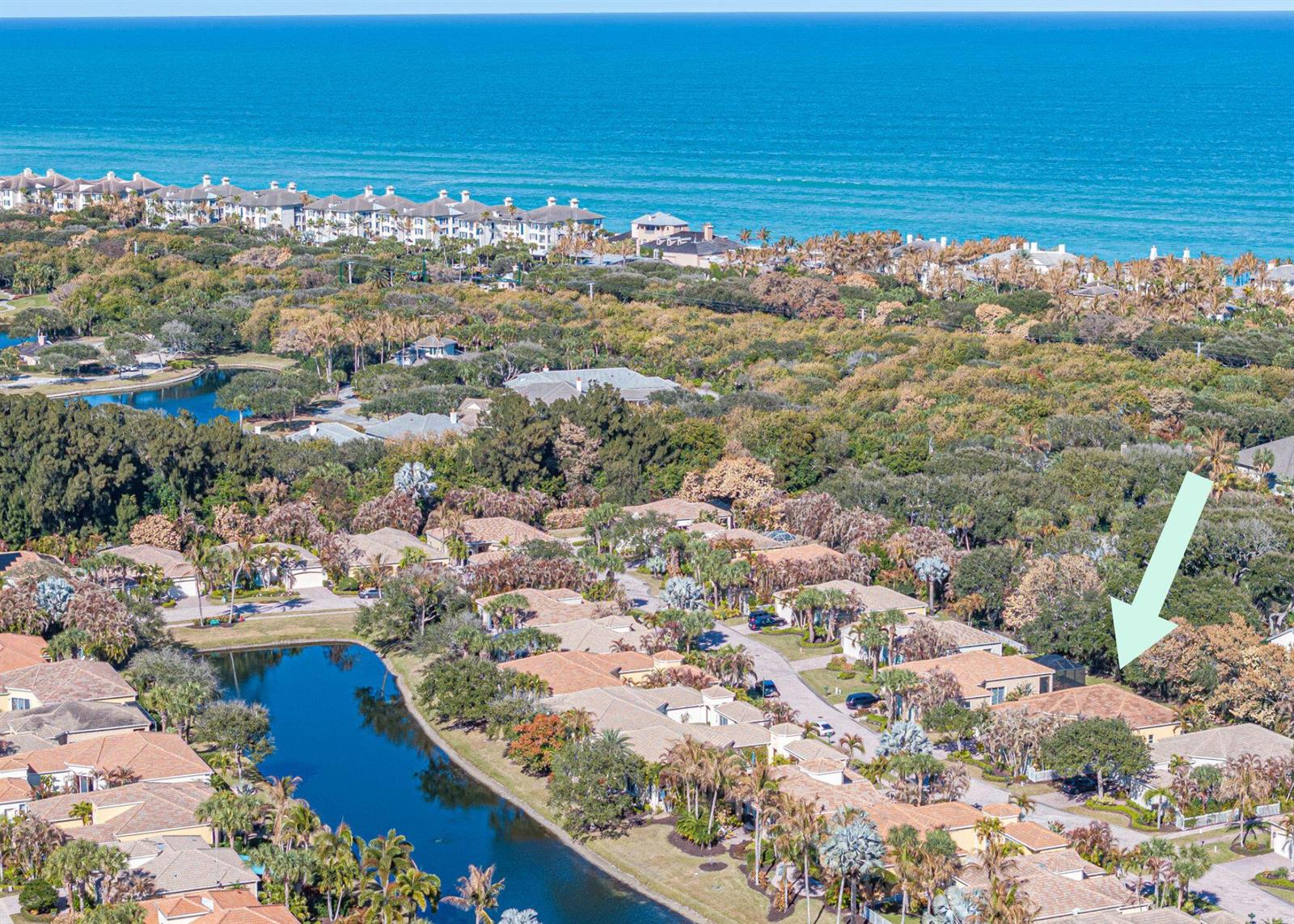 An aerial view shows a residential neighborhood with houses, a pond, and the ocean — 9630 E Maiden Court, Vero Beach FL 32963, VERO BEACH, FL