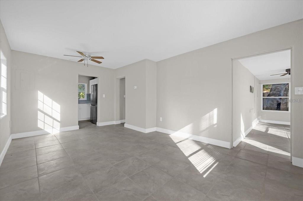 A bright, empty living room with gray tile flooring, white walls, and a ceiling fan — 907 COLUMBIA STREET, ORLANDO, FL