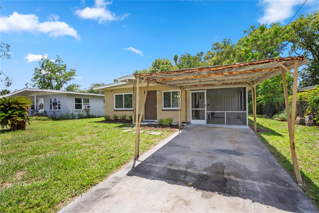 A tan house features a screened-in porch and a rusted metal carport over a concrete driveway — 5212 N INDIANA AVENUE, WINTER PARK, FL