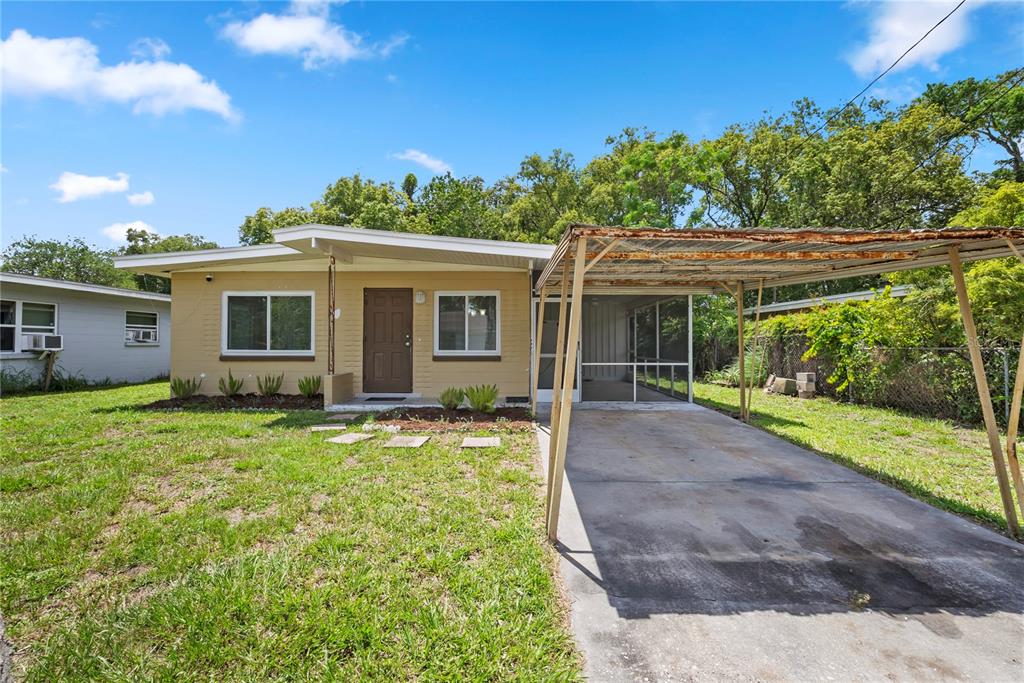 A single-story house with a tan exterior, a brown front door, and a metal carport — 5212 N INDIANA AVENUE, WINTER PARK, FL
