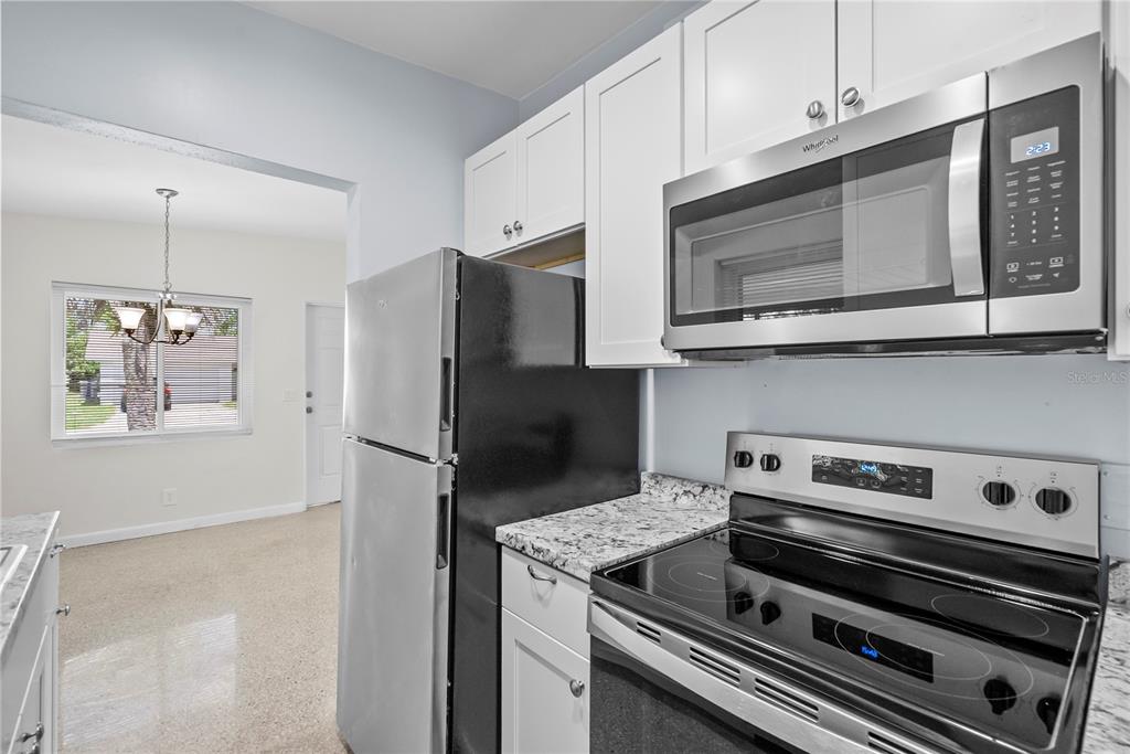 A kitchen features white cabinets, granite countertops, stainless steel appliances, and a black refrigerator — 5212 N INDIANA AVENUE, WINTER PARK, FL