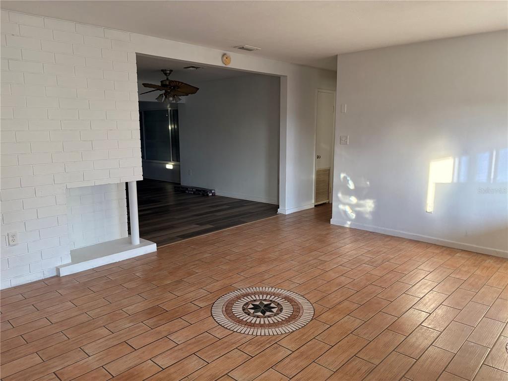 A living room features light-colored tile flooring with a decorative medallion and a white fireplace — 719 HILLSIDE AVENUE, LAKE WALES, FL