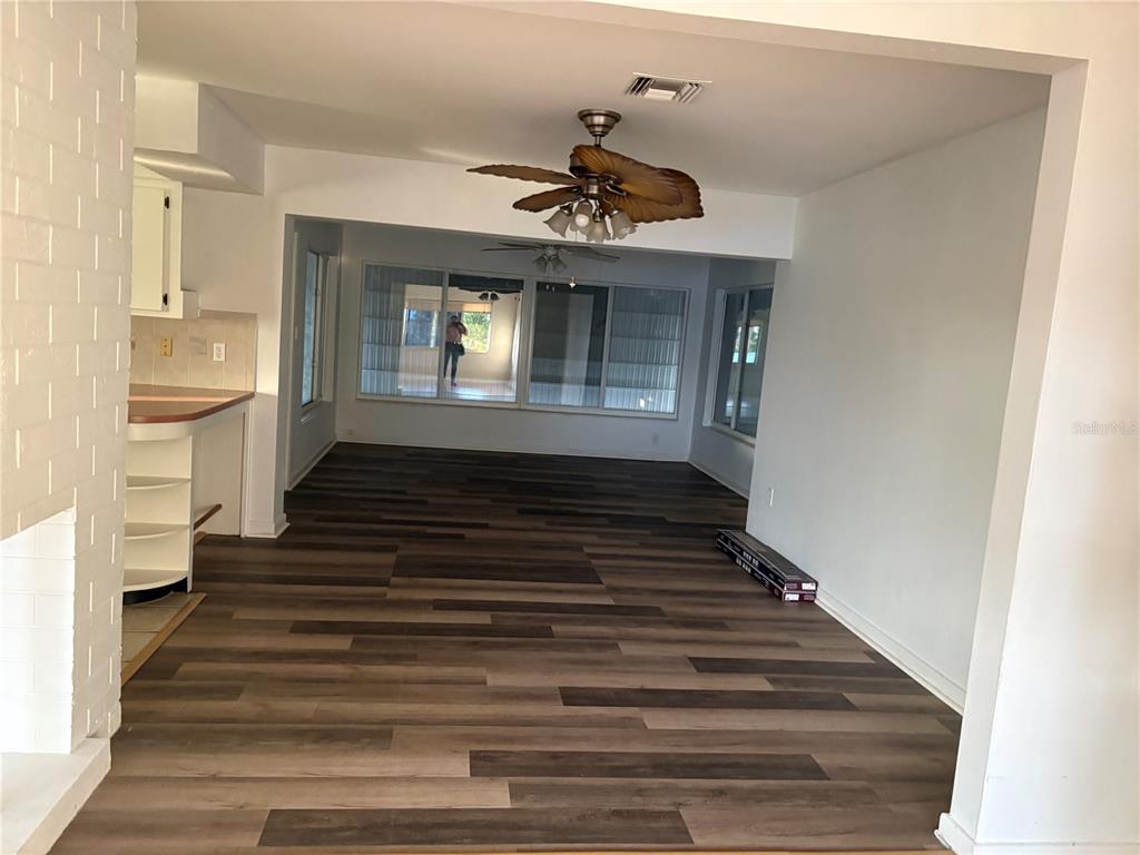 An open-concept living area features wood-look flooring, a ceiling fan, and large windows — 719 HILLSIDE AVENUE, LAKE WALES, FL
