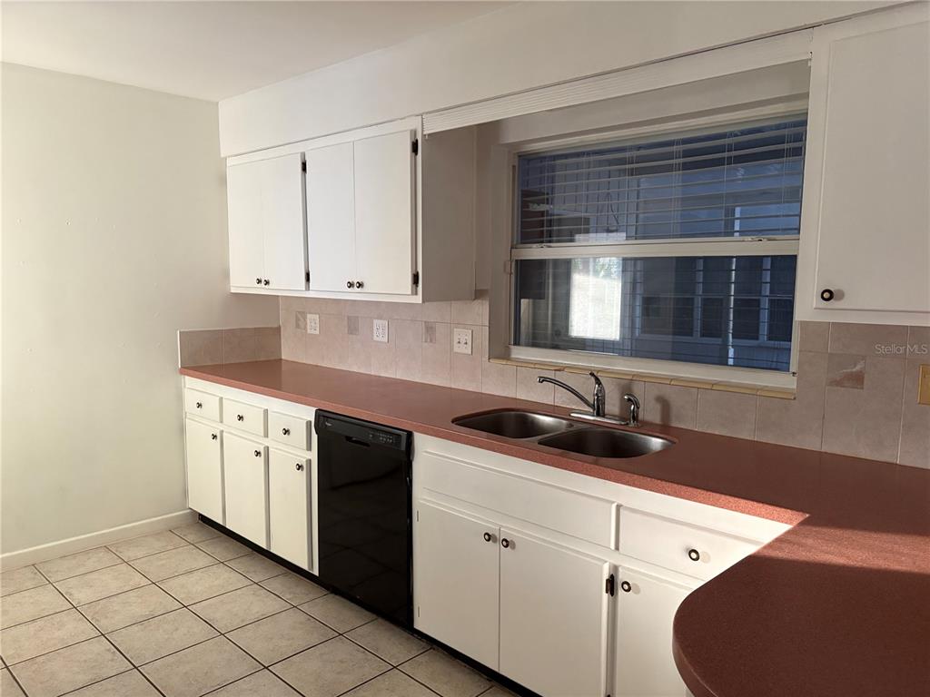 A kitchen features white cabinets, a red laminate countertop, a double sink, and tile flooring — 719 HILLSIDE AVENUE, LAKE WALES, FL