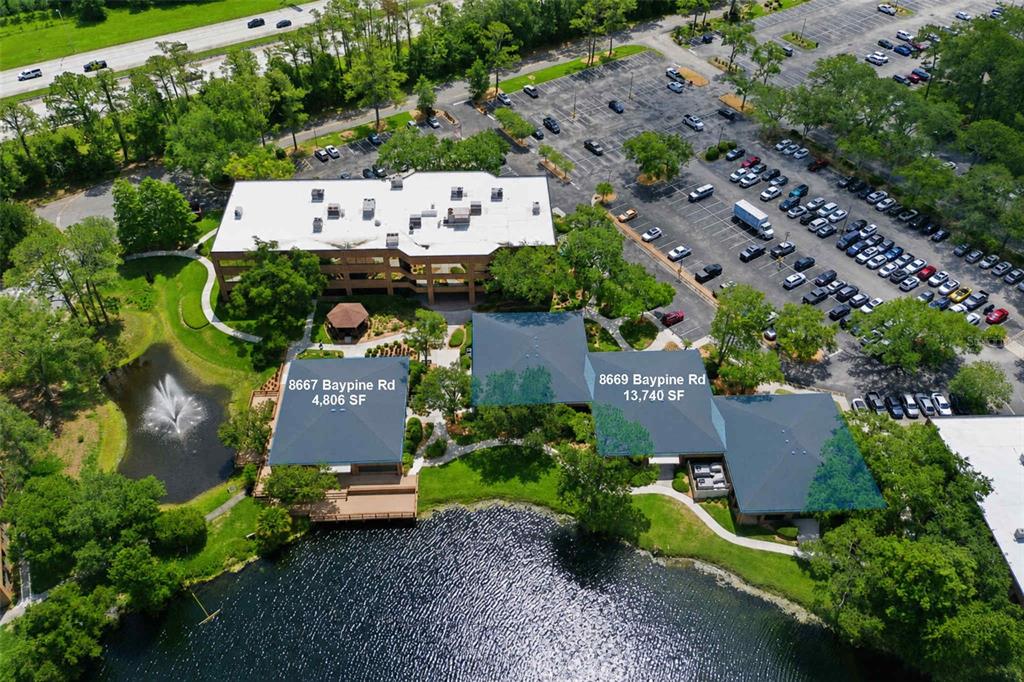 An aerial view shows office buildings with parking lots and a pond with a fountain — 8669 BAYPINE ROAD, JACKSONVILLE, FL