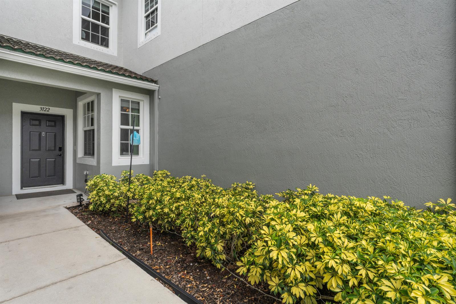 A gray exterior wall sits next to a front entrance with a dark door — 3122 Grandiflora Drive, FL 33467, FL