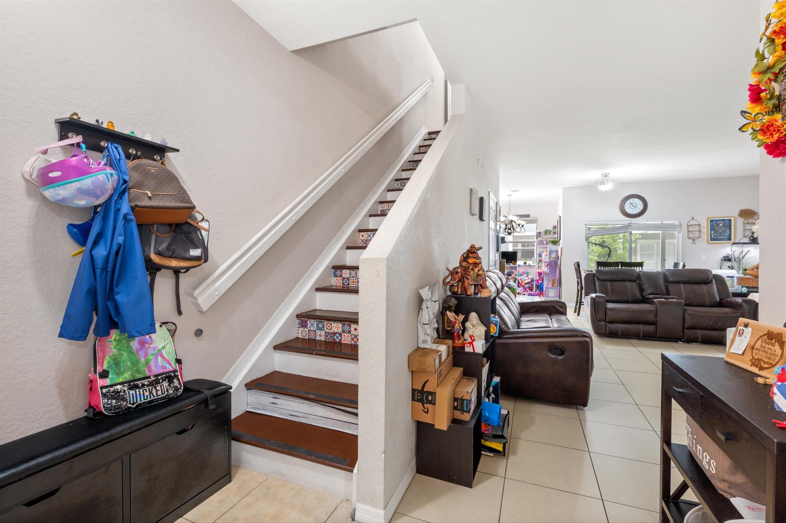 A staircase with patterned risers leads upward next to a living room with brown furniture — 3122 Grandiflora Drive, FL 33467, FL