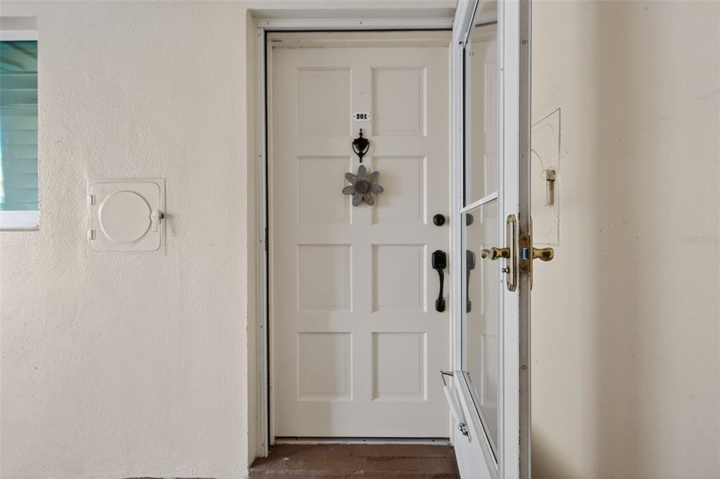 A white front door with a decorative flower and number 201 is partially open — 1200 N SHORE DRIVE NE UNIT 201 furnished, ST PETERSBURG, FL